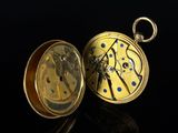 a close up of a pocket watch on a black surface