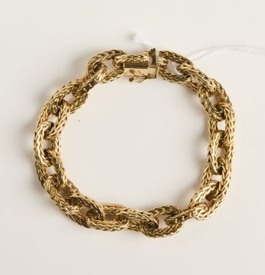 gros plan d'un bracelet en chaîne en or sur une surface blanche
