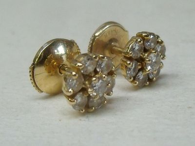 une paire de boucles d'oreilles à clous en diamant posées sur une surface blanche