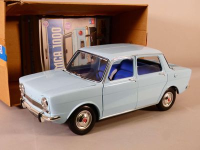 une petite voiture miniature dans une boîte, avec une autre boîte en arrière-plan