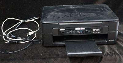 une imprimante noire posée sur une surface noire à côté d'un chargeur