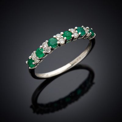 une bague en émeraude et diamant sur une surface noire