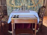 une table et des chaises dans une pièce où est accrochée une tapisserie au mur
