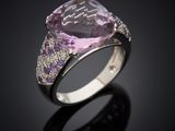 a pink sapphire and diamond ring on a black surface