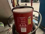 un extincteur rouge posé sur un chariot dans un garage