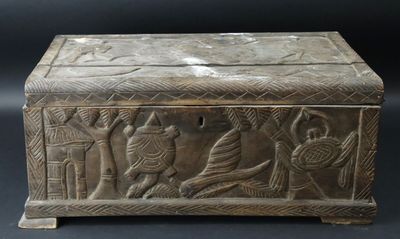 an old wooden box with carvings on it sitting on a black surface