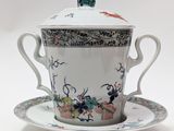 une tasse et une soucoupe posées sur une soucoupe, surmontées d'un oiseau