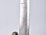 a close up of a sword on a table with a white background