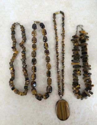 plusieurs colliers et bracelets composés de perles en œil-de-tigre, posés sur une table