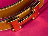 a close up of a brown belt on a pink surface