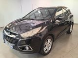 Une voiture noire est garée dans un garage aux murs blancs.