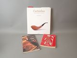 trois livres et une pipe posés les uns à côté des autres sur une table