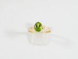 un gros plan d'une bague en tourmaline verte sur une surface blanche
