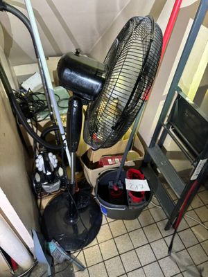 a fan that is sitting on the floor next to a bucket