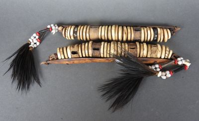 trois morceaux de bois ornés de perles noires et blanches et d'une plume