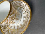a gold and white cup and saucer sitting on a table