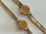an image of two gold colored watches on a white surface