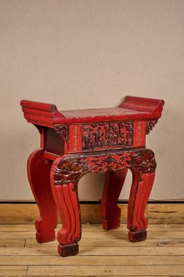 un petit tabouret rouge posé sur un plancher en bois
