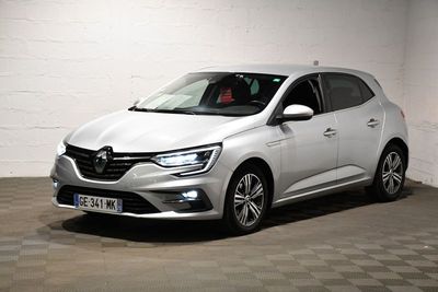La voiture blanche est garée dans un garage dont le sol est en damier.