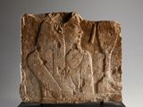 an ancient stone relief of a man and a woman on a pedestal