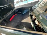 a green truck with its trunk open and a red object in the trunk
