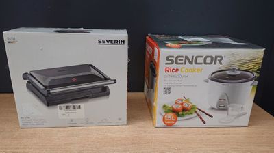 two boxes of food are sitting on a table next to a box of rice cookers