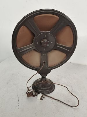 Un ventilateur à l'ancienne est posé sur une table, avec un cordon d'alimentation