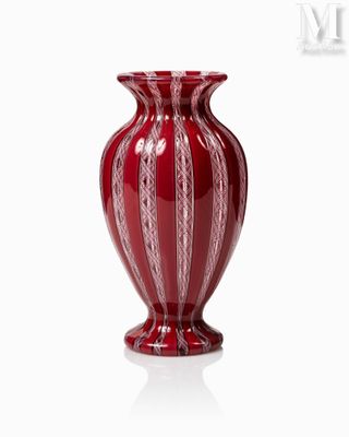 un vase rouge posé sur une surface blanche