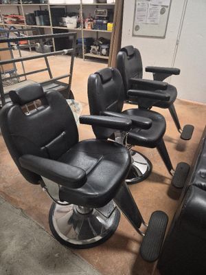 quatre fauteuils de coiffeur noirs dans une pièce où se trouve une échelle