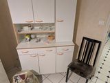 une cuisine blanche avec une chaise noire et une horloge accrochée au mur