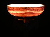 a close up of a wooden bowl lit by a candle in the dark