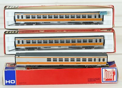 trois trains miniatures sont empilés les uns sur les autres sur une table