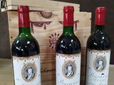 trois bouteilles de vin rouge sont posées devant une caisse en bois