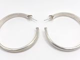 une paire de boucles d'oreilles créoles en argent sur fond blanc