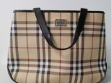 beige and black plaid purse sitting on a table with a white wall