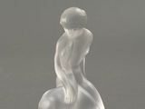 deux figurines en verre représentant un homme et une femme assis sur un rocher