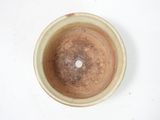 a brown bowl sitting on a white surface with a white dot in it