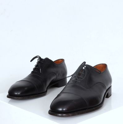 chaussures en cuir noir avec lacets sur une surface blanche