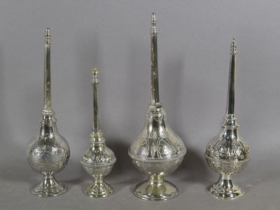 trois bougeoirs en argent et un porte-bougie posés sur une table