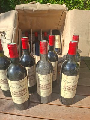 several bottles of wine sitting on a wooden table next to a brown bag