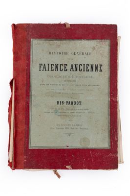 un vieux livre à la couverture rouge posé sur une surface blanche