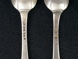 three silver spoons sitting next to each other on a black surface