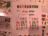 a lot of stamps on a table with a person holding a pen