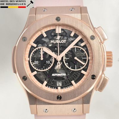 La montre est rose et dorée, avec un cadran noir.