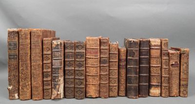 several old books are lined up in a row on a gray surface