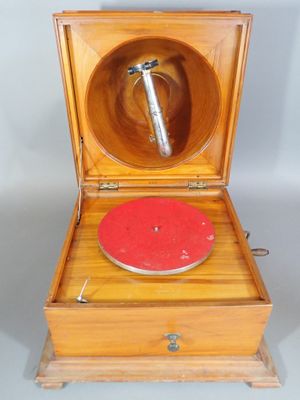 un vieux tourne-disque en bois avec un disque rouge dans un coffret en bois