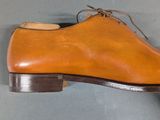 pair of brown leather shoes with laces on a gray surface