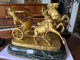 a gold statue of a man riding a horse drawn carriage
