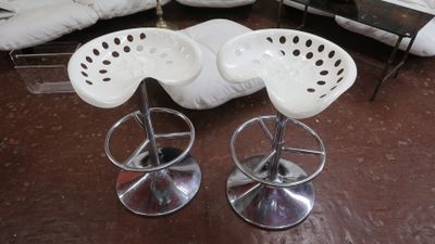 trois tabourets blancs posés sur un parquet, à côté d'un canapé blanc