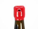 a close up of a bottle of wine with a red cap